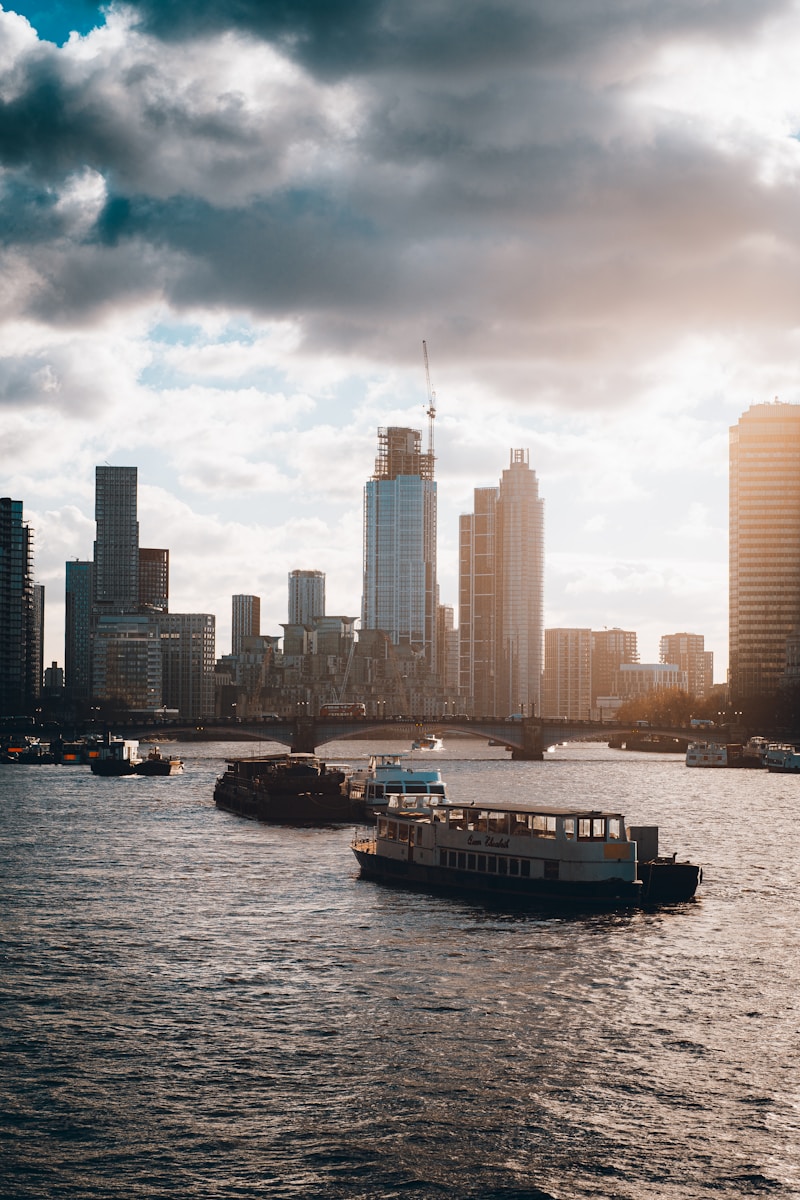 a boat traveling down a river next to a large city