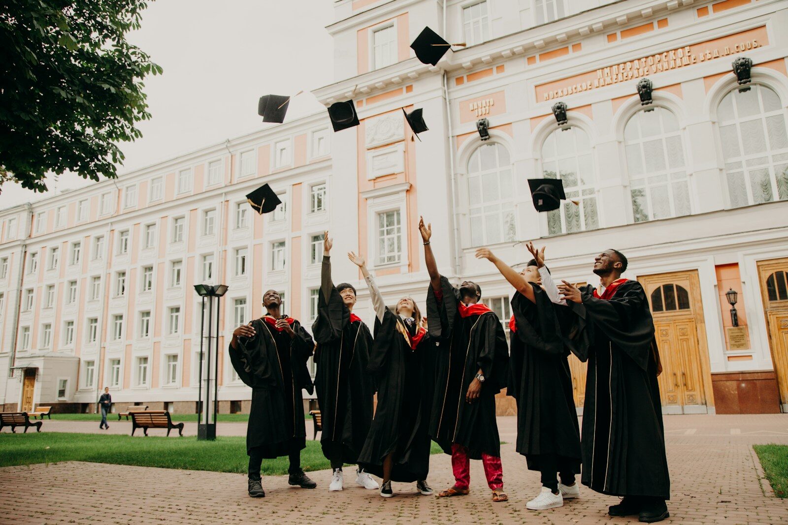 A group of graduates in black robes throwing their caps in the air